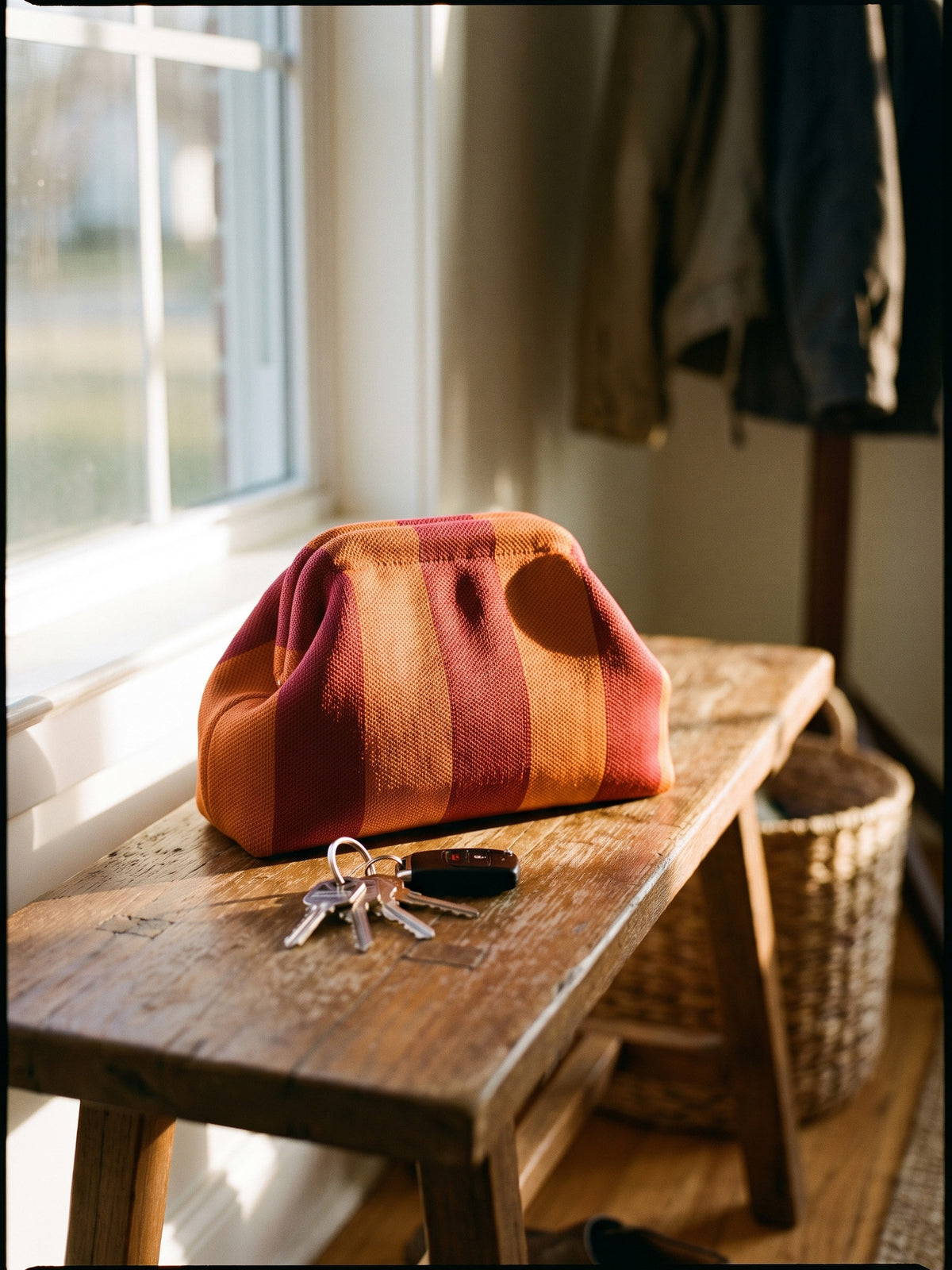 Rust & Orange Stripe Cloud Pouch — rests on a wooden entry bench beside a set of keys