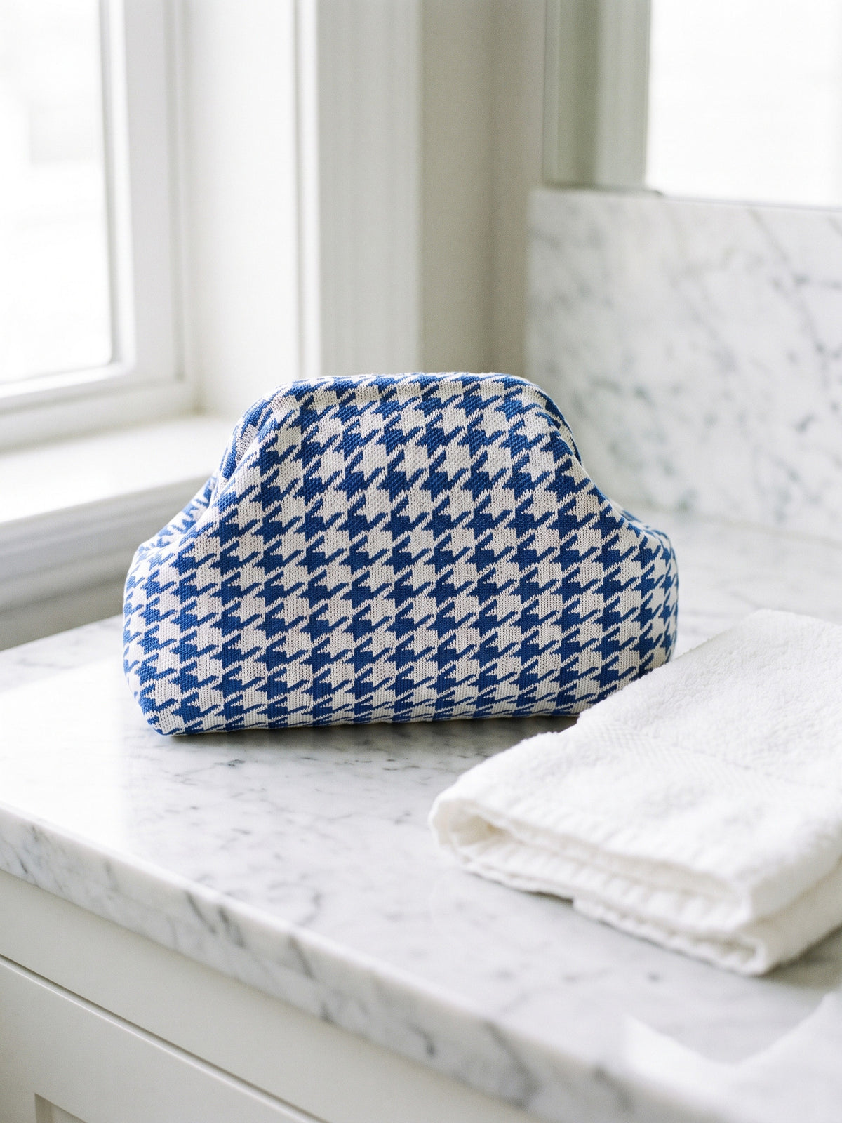 Cobalt Houndstooth Cloud Pouch — sits on a marble counter beside a folded hand towel of similar width