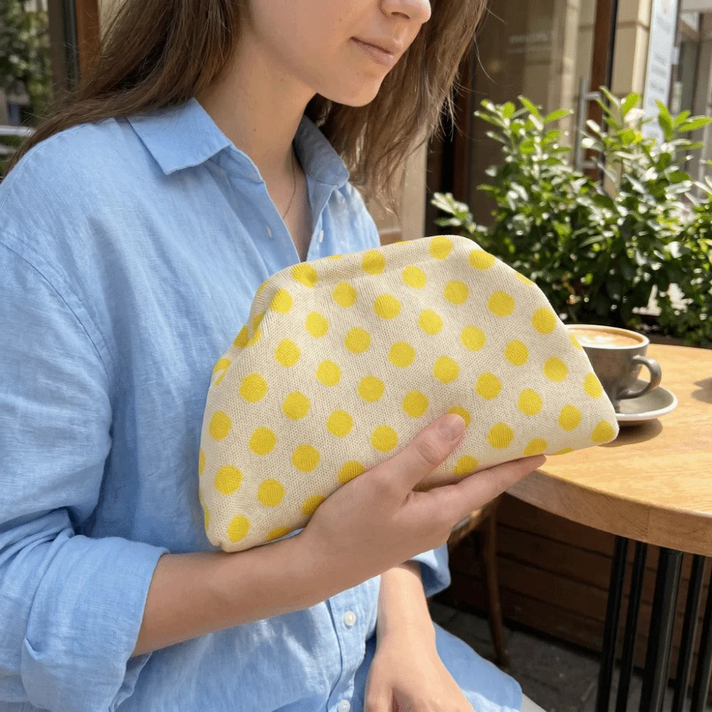 Lemon Polka Dot Cloud Clutch held at a café table