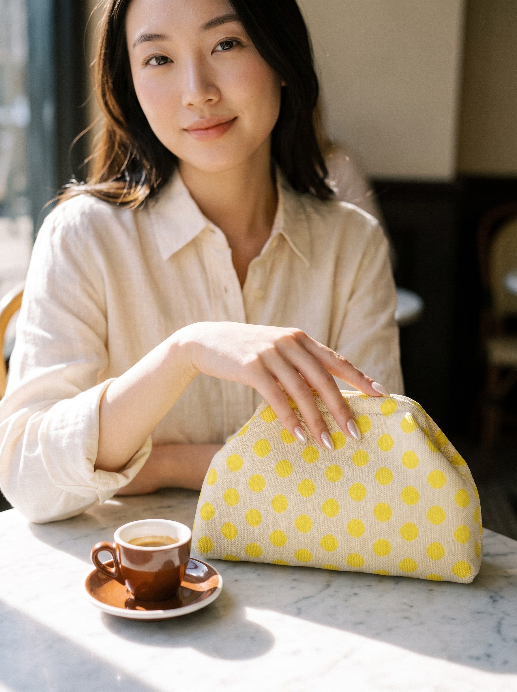 Lemon polka dot clutch on a café table
